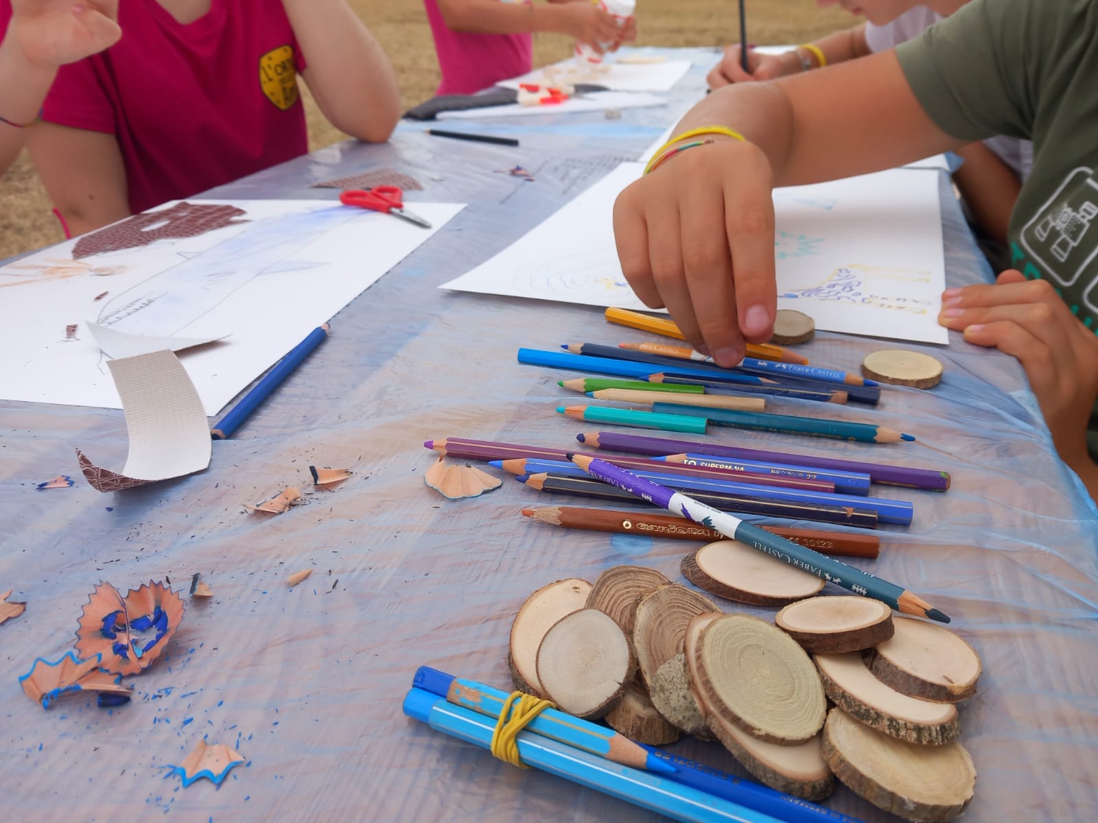 Bambini che disegnano e colorano all'aperto con matite e dischetti di legno